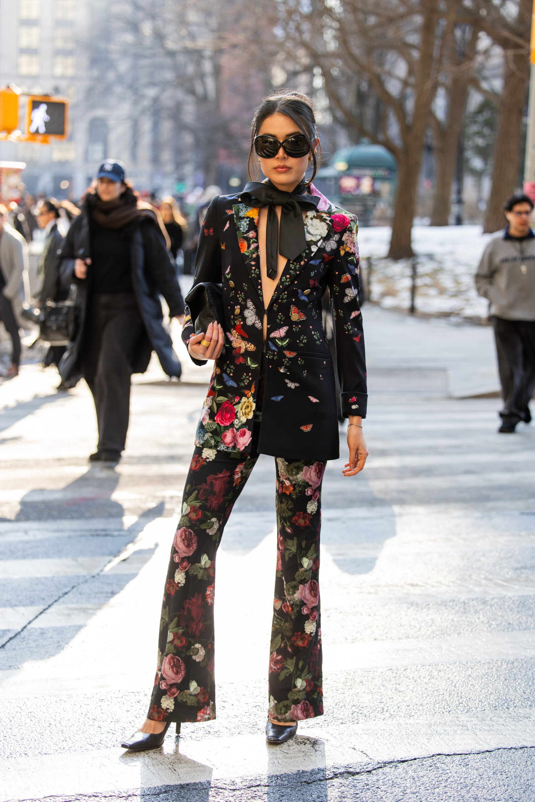 A guest wears blazer, flared pants with floral print.