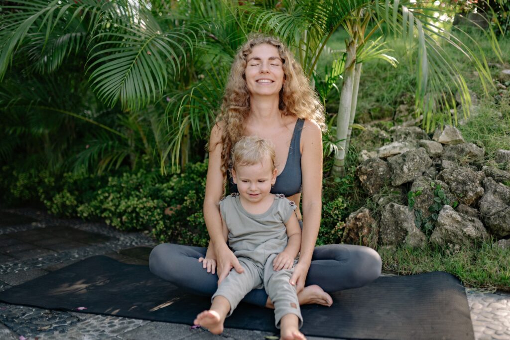 Μαμά και παιδί κάνουν yoga στην αυλή.
